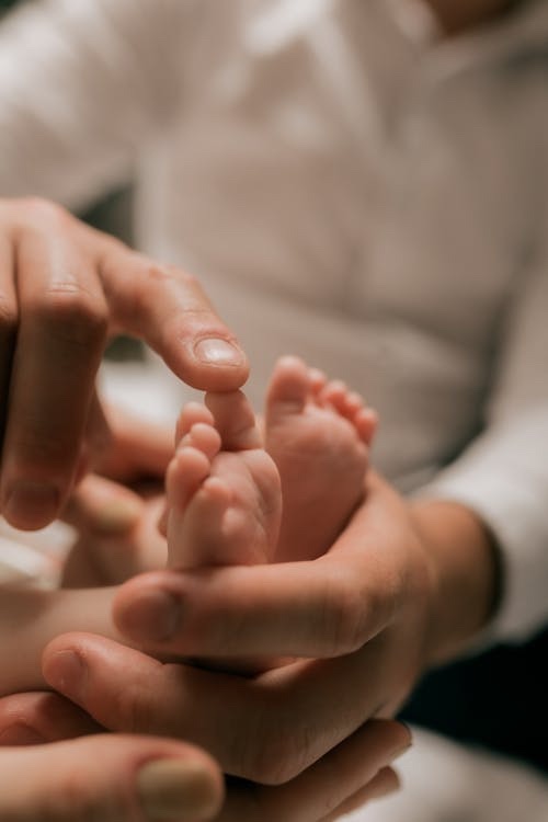 Adult hands gently holding a newborn's foot
