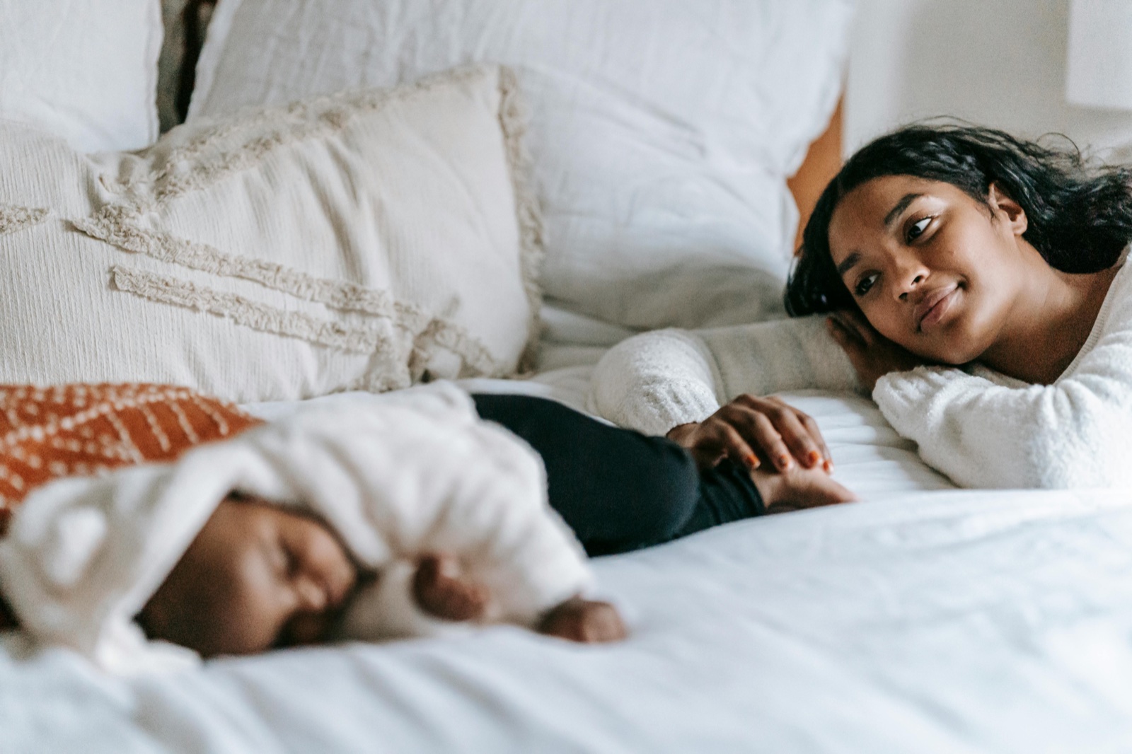 Parent resting beside a sleeping baby